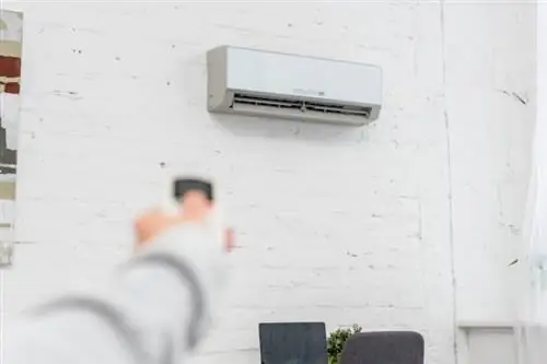 Woman adjusts air conditioner with remote control