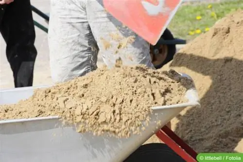 Vul zand in de kruiwagen met een schep